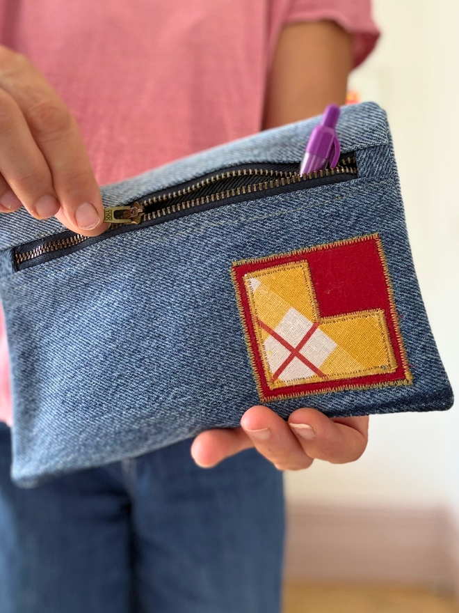 Handmade pencil case made from reclaimed denim with a zip fastening and a bright vintage‑print initial on the front
