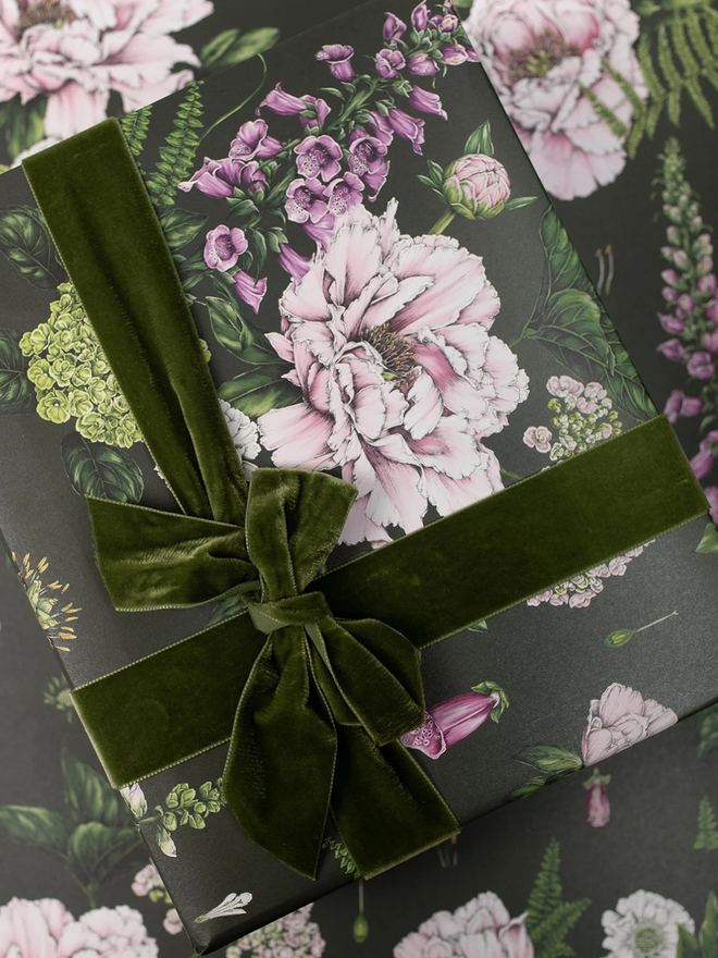 summer garden gift wrap sheet. a box wrapped in dark green illustrated floral gift wrap with a green ribbon.
