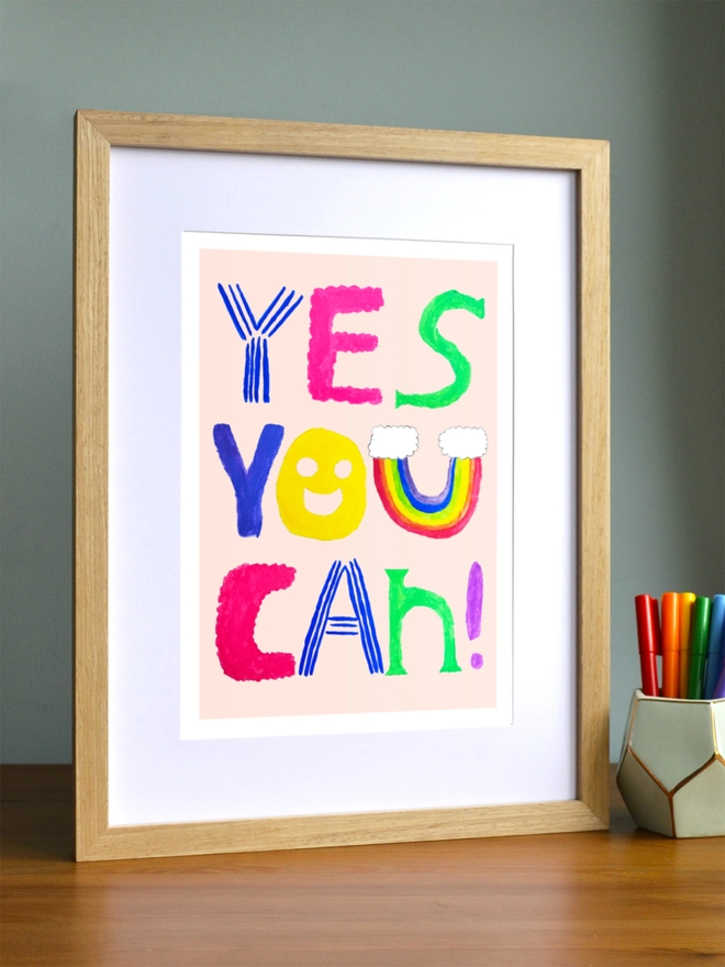Art print saying 'Yes you can' in a brown frame in a child's room