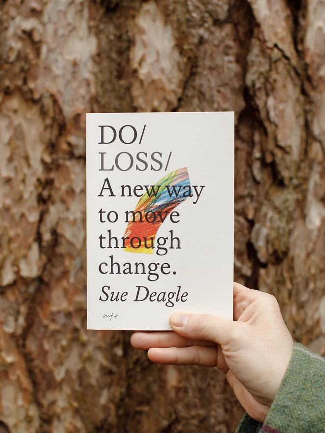 Paperback book held up against tree bark