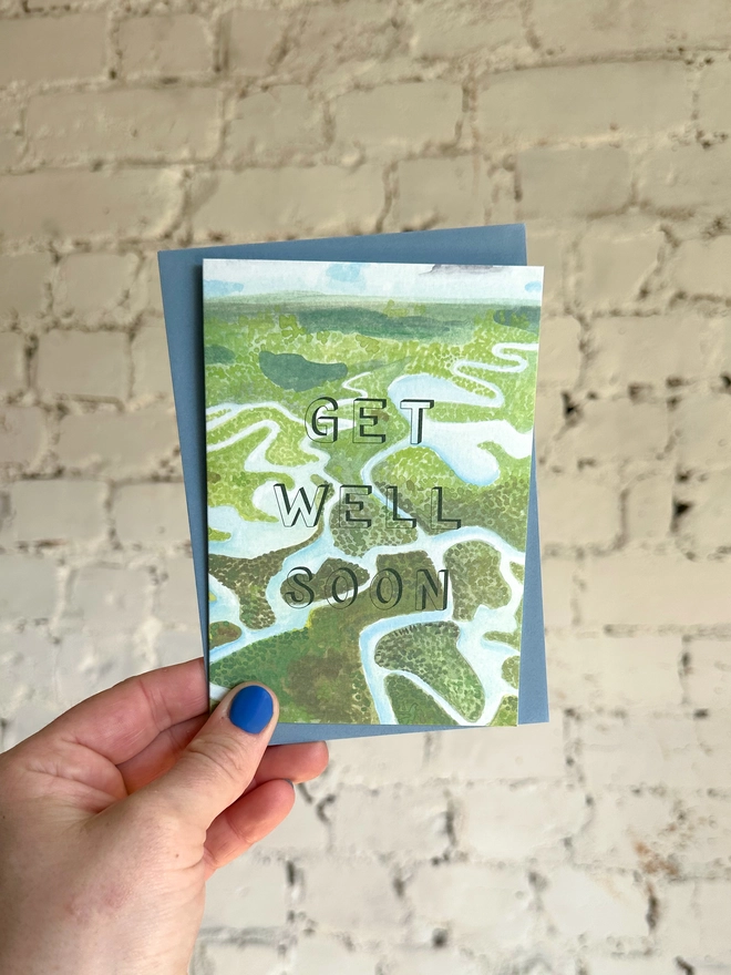 a greetings card featuring an illustration of the Everglades National Park with the text “GET WELL SOON” with a blue envelope