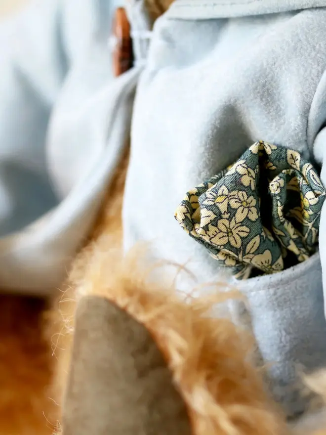 Handmade teddy bear with soft textured fur, wearing a blue jacket, posed against a plain background.