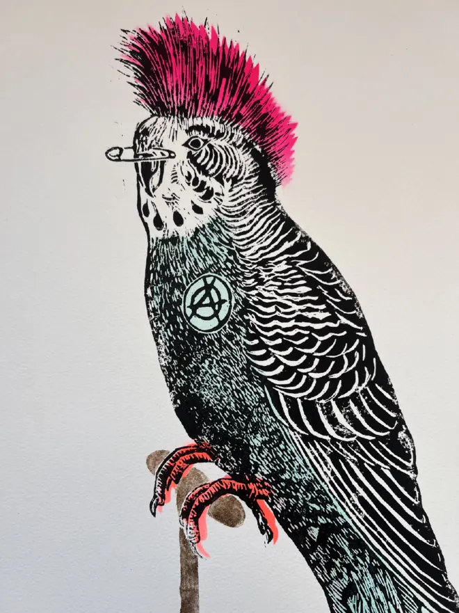 Punk budgie lino print, with symbols, coloured with blue and pink paint with on a white background. 