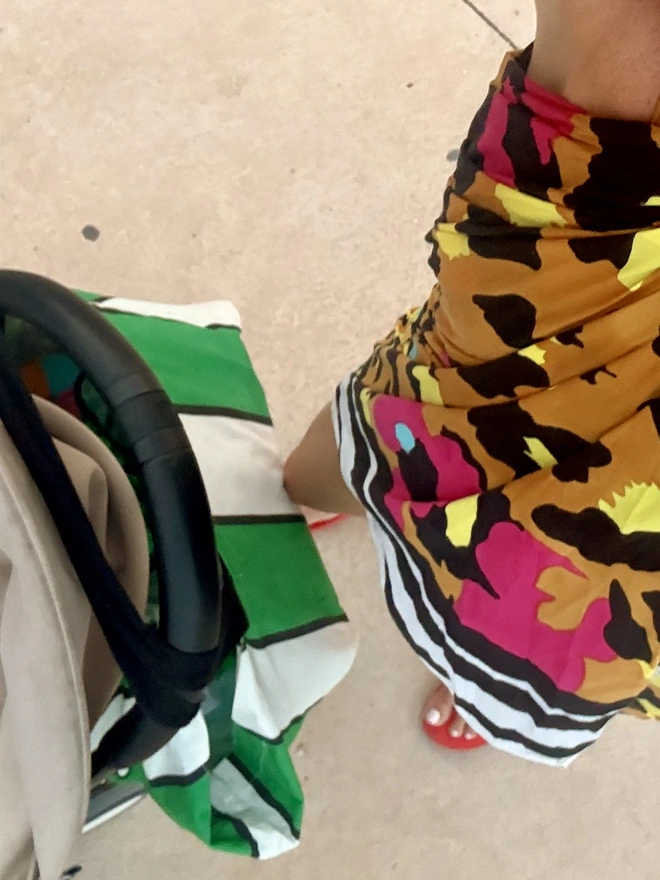 Green stripes bag on pram handles at the beach 
