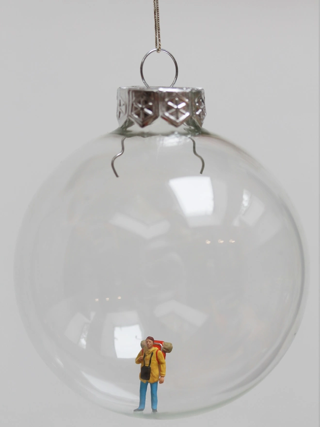 Miniature figure of a backpacker in a glass Christmas bauble 