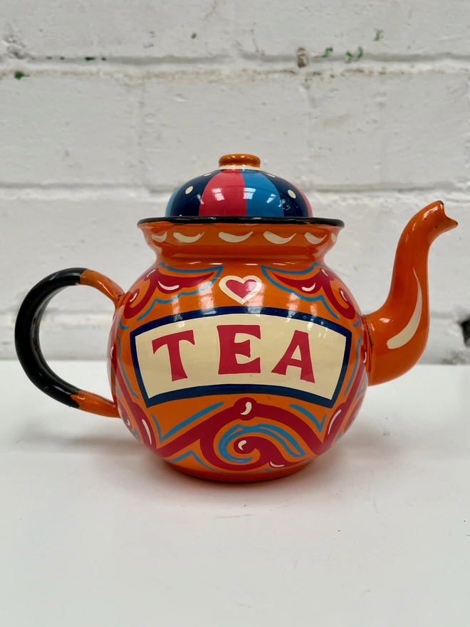 Small orange vintage teapot, hand painted with a design inspired by traditional scrollwork.