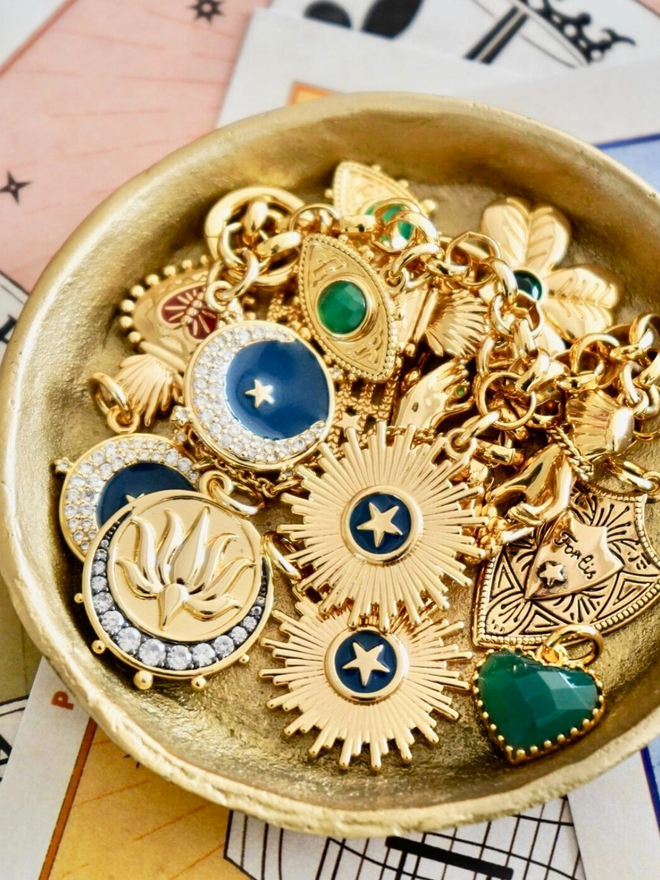 Collection of gold and colourful charms in a small gold bowl