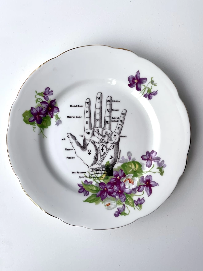vintage plate with an ornate border, with a printed vintage illustration of a palm reading hand of fate in the middle 