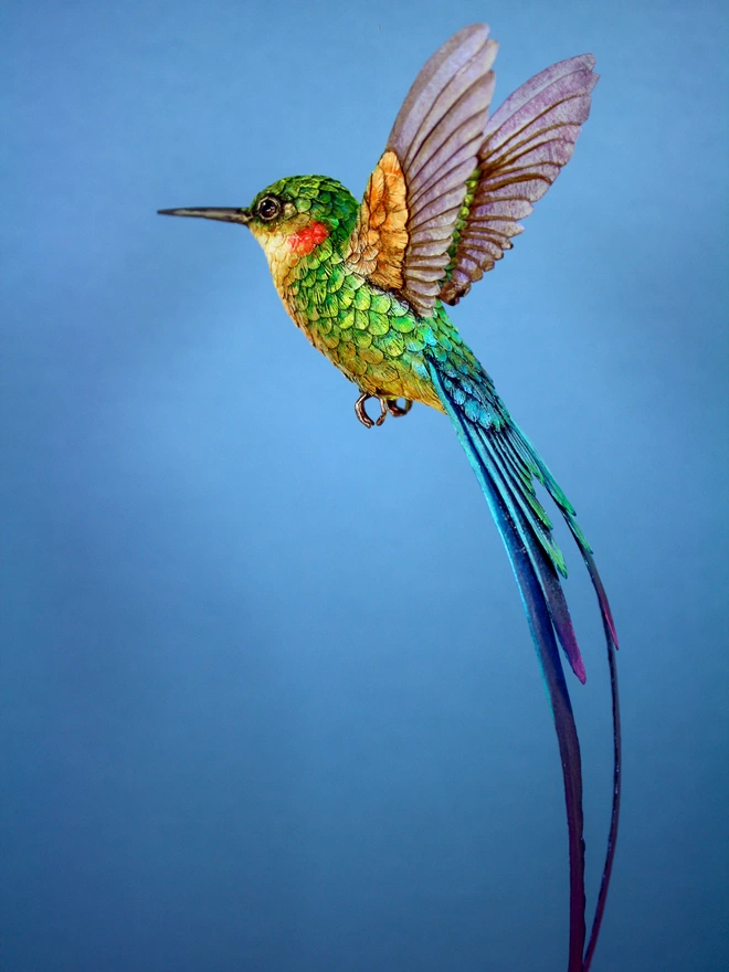 Paper hummingbird sculpture on blue background