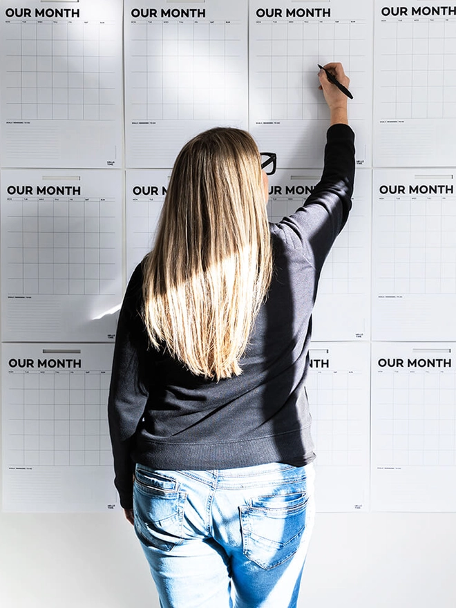 Wall planner sheets on the wall, female writing on the sheets