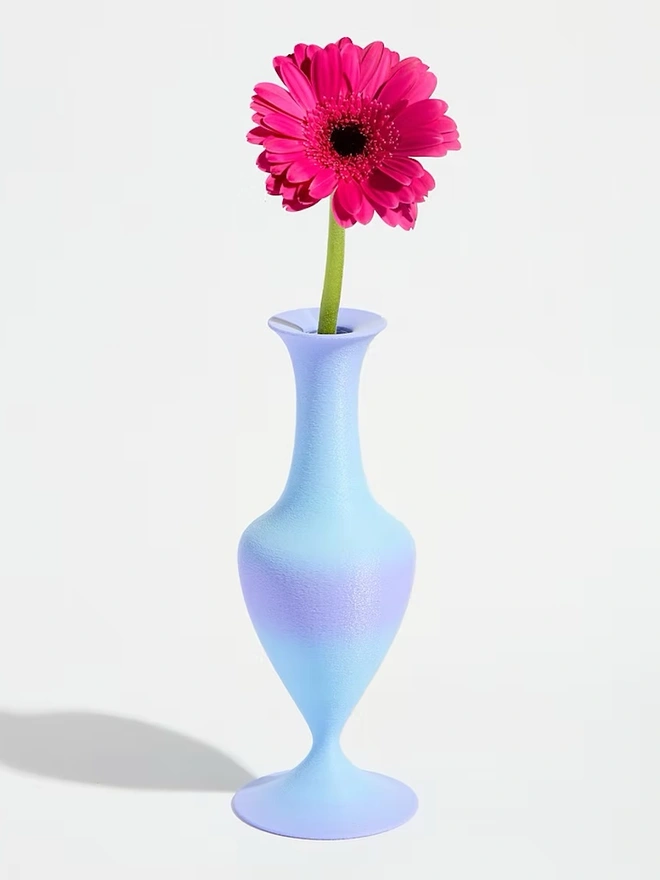 3d printed vase in blue and purple stripes with bright pink flower
