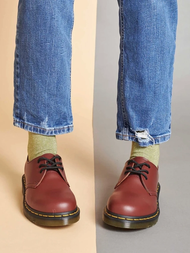 Women's Glitter Organic Cotten Ankle Socks, a woman wearing a pair of colourful patterned socks above a decorated surface. 