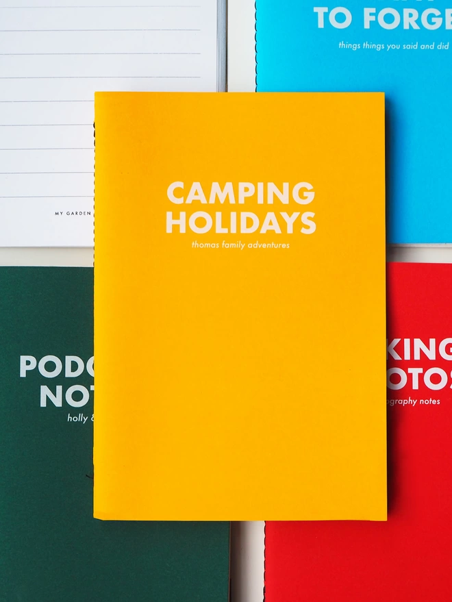 a yellow coloured notebook with the text camping holidays written on the front in bold white ink