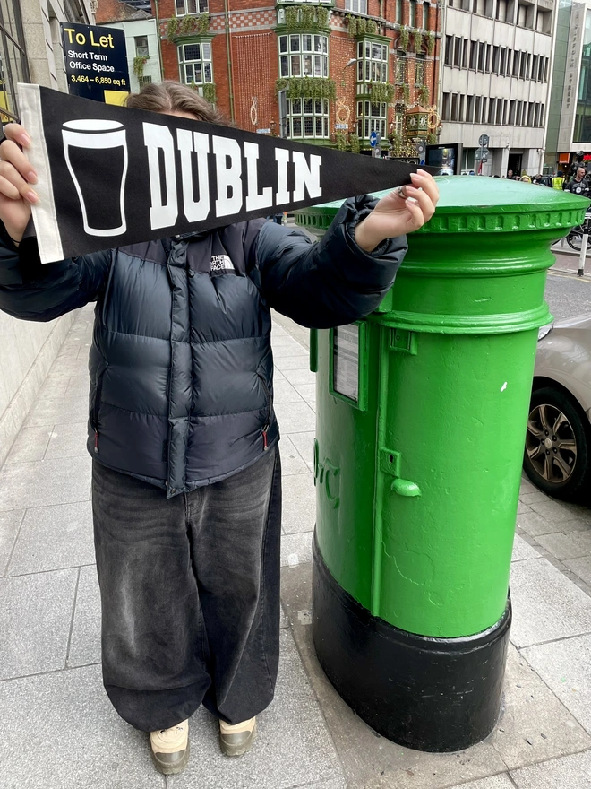 a felt pennant flag black and white, it has the word DUBLIN written in the varsity style and a pint of Guiness next to it