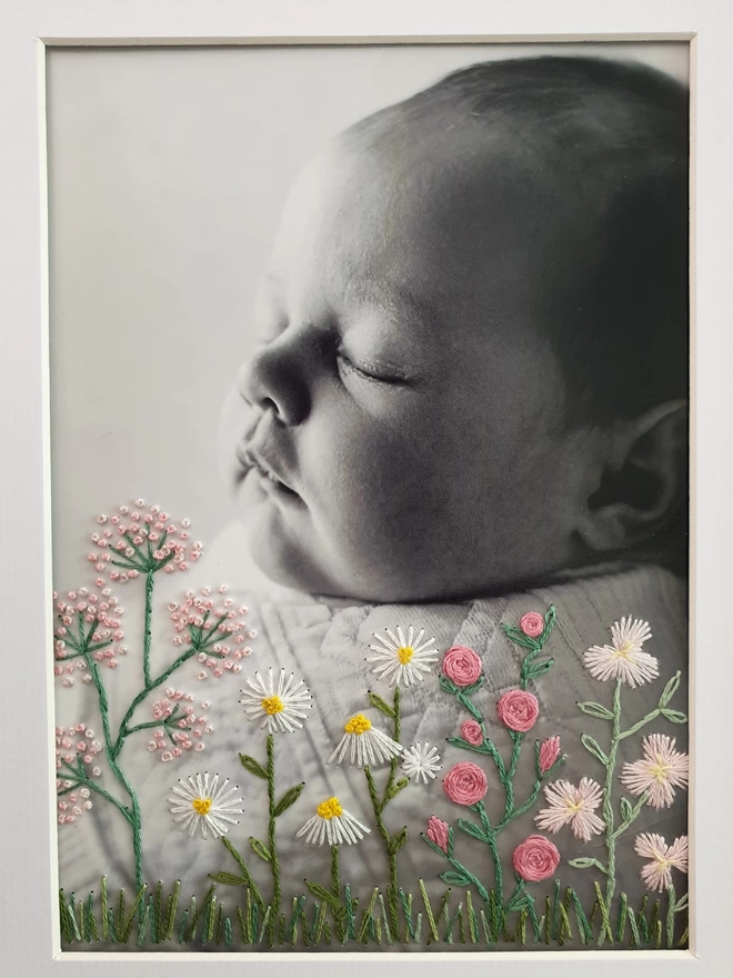Close up image of baby photo with hand embroidered flowers along bottom 