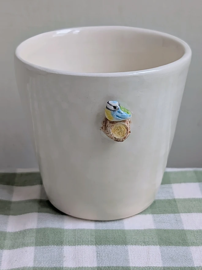 blue tit espresso coffee cup with a tiny handmade bird resting on a small ceramic wooden tree branch in white earthenware pottery