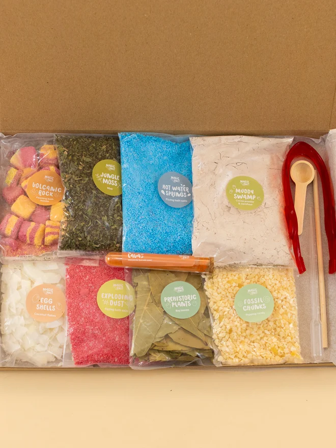 dino sensory potion kit. nine bags of assorted sensory materials placed into a cardboard box.