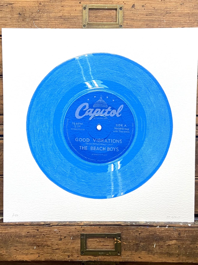 The Beach Boys Good Vibrations Blue Vinyl Screen Print leaning on a shelf