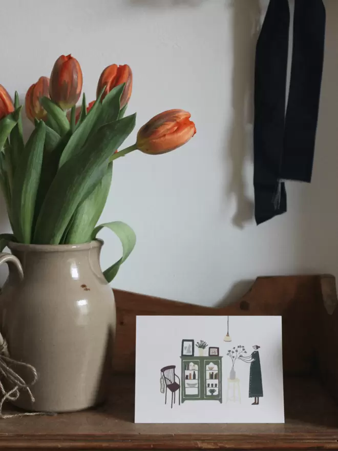 greetings card next to a vase of orange tulips
