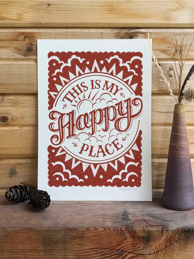 red happy place print in wood cabin with dried grasses and fir cones