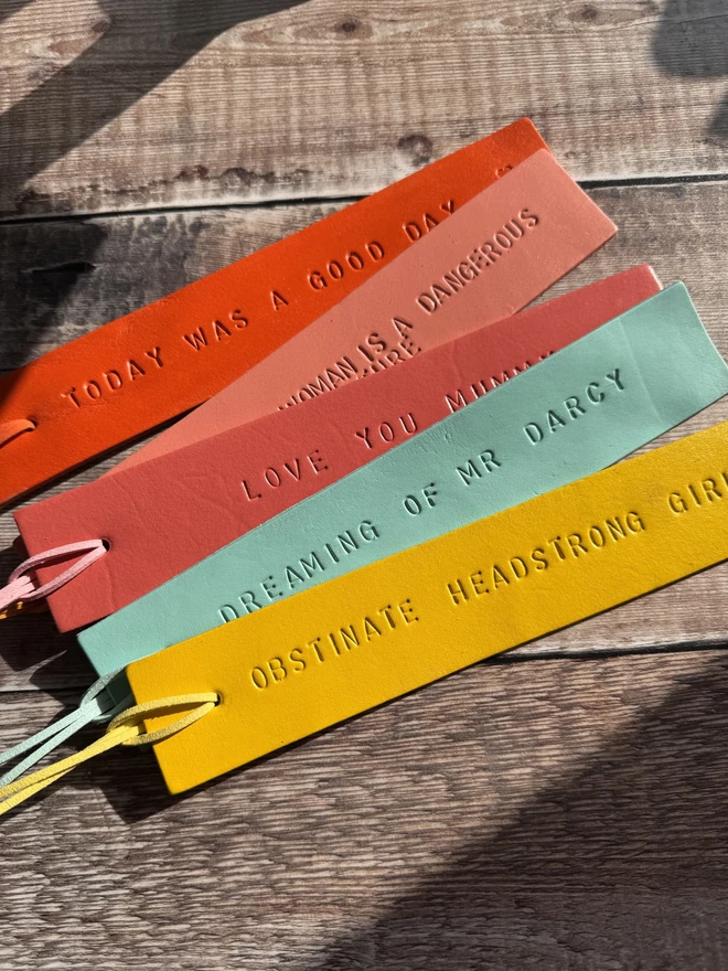 Colourful hand-painted leather bookmarks with embossed quotes, each featuring a leather tie. A stylish and durable accessory for book lovers, perfect as a personalised gift