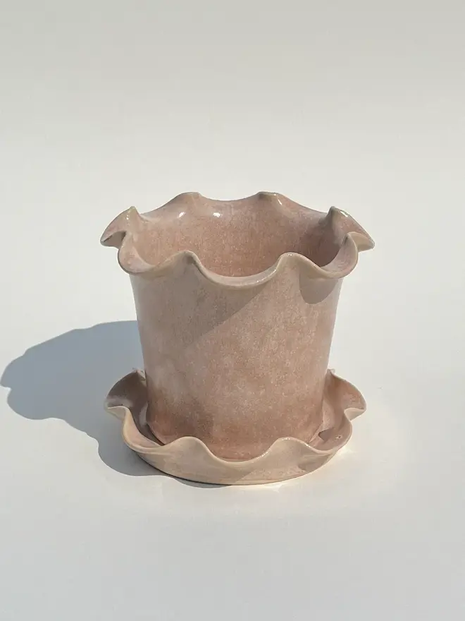 Frilly Plant Pot And Saucer, a collection of colourful plant pots sitting on a plain surface. 