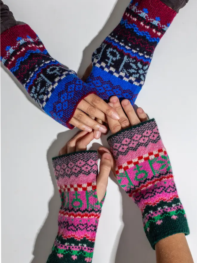 Two models reach across a table to hold hands. Both are wearing fairisle wrist warmers, one  wears the colourway klein, the other wears bubblegum