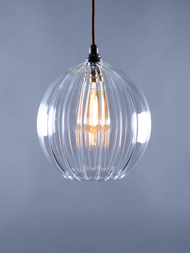 Medium Size Wanda Clear Ribbed Glass Pendant Light. Light on. 
