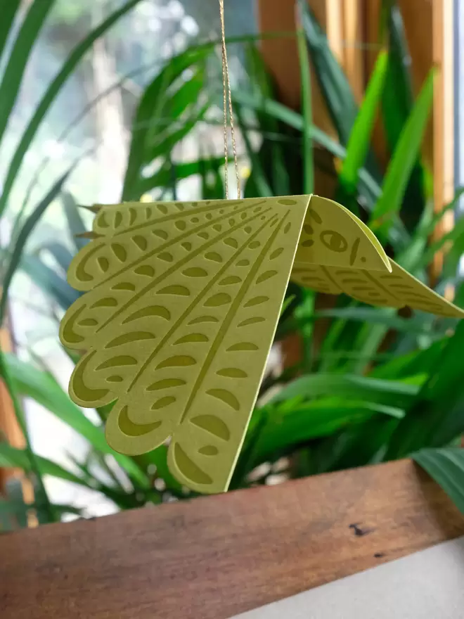 Green hanging letterpress printed bird with gold thread.