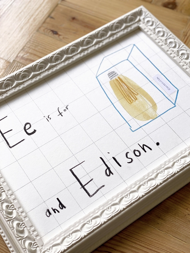 framed drawing of Edison lightbulb and hand written E for Edison in white frame 