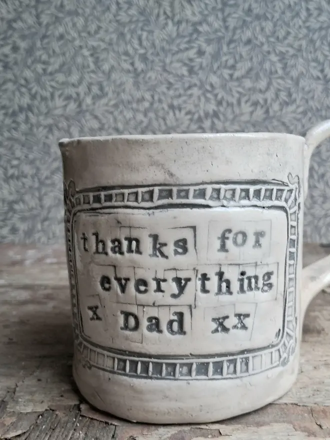 personalised message ceramic mug. a ceramic mug engraved with a personalised linocut message on the front, reading 'thanks for everything dad'.