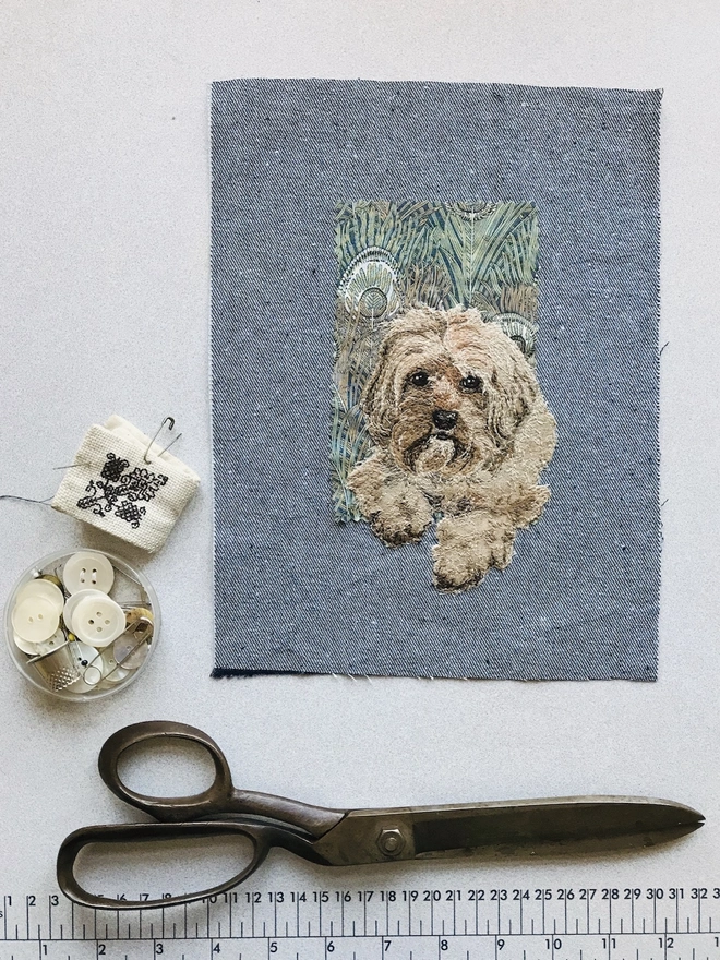 picture of a small embroidered pet portrait on a sewing desk