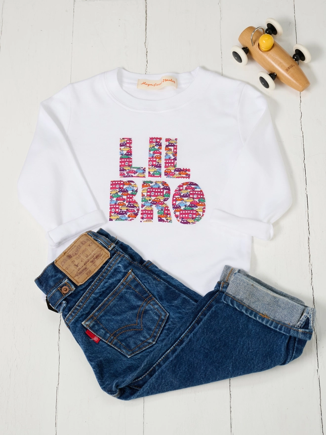 a white kids t-shirt with Lil Bro sewn on in letters cut from Liberty cars print 