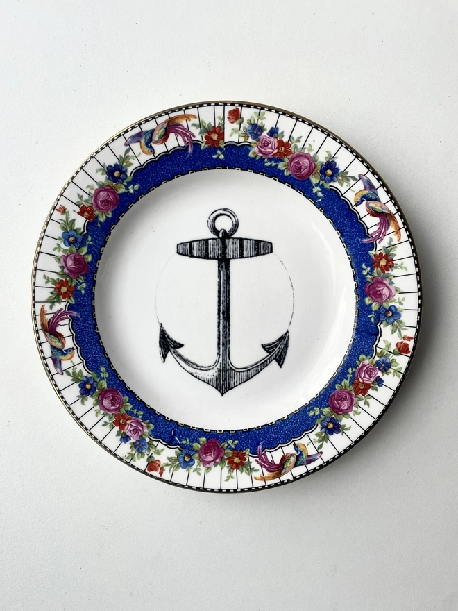 vintage plate with an ornate border, with a printed vintage illustration of an ship's anchor in the middle 