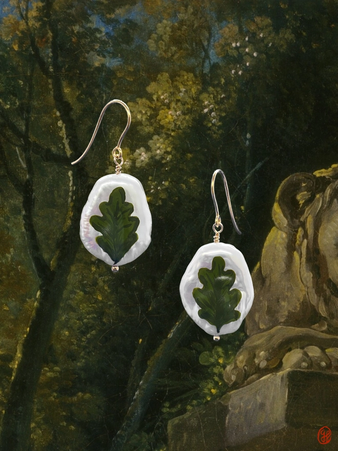 A pair of flat pear shaped pearl drop earrings with green oak leaf motif painted on the front, set in 9ct gold.