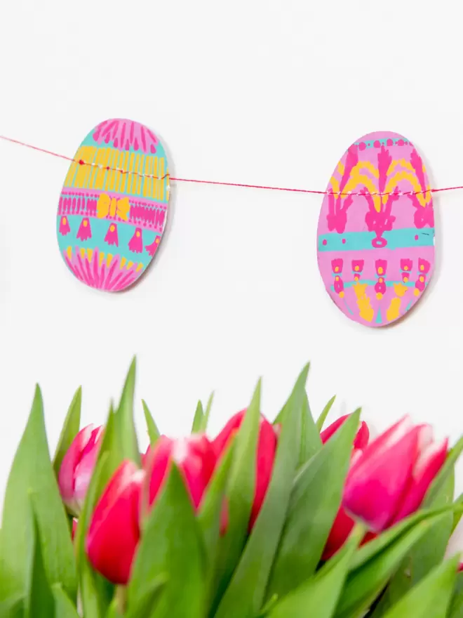 Close up of pink decorations on white wall with real pink flowers