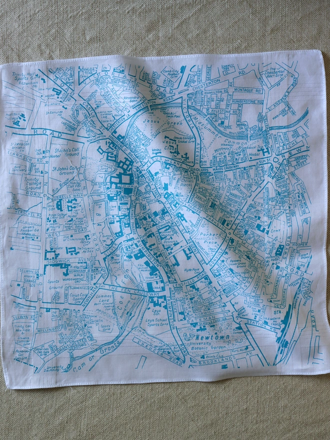 A Mr.PS Cambridge map hankie printed in aqua laid flat on a linen tablecloth