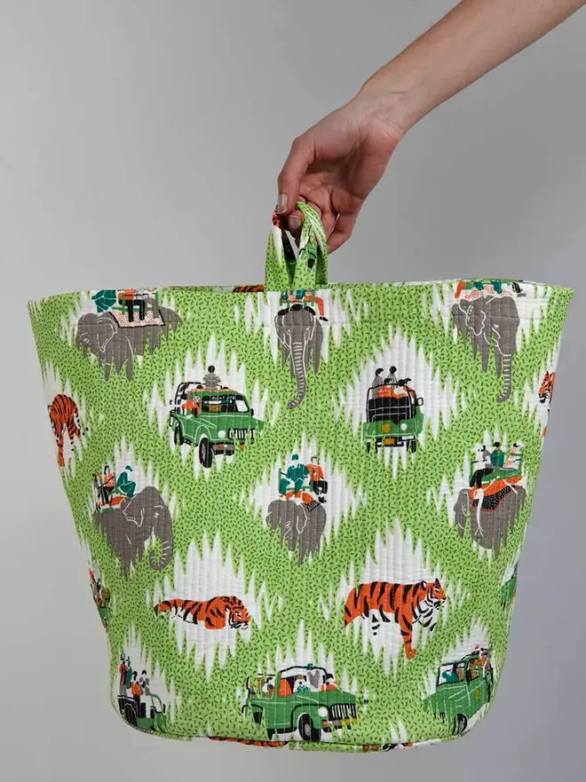 Tiger Safari Quilted Storage Basket, a person holding a green safari basket against a grey backdrop. 