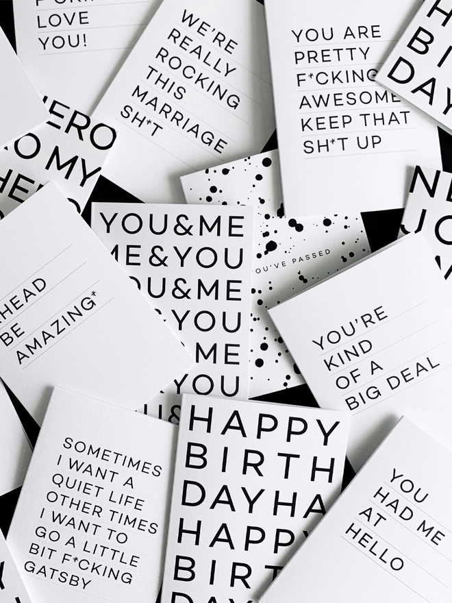 Examples from the range of HELLO TIME greetings cards overlapping each other on a black background.
