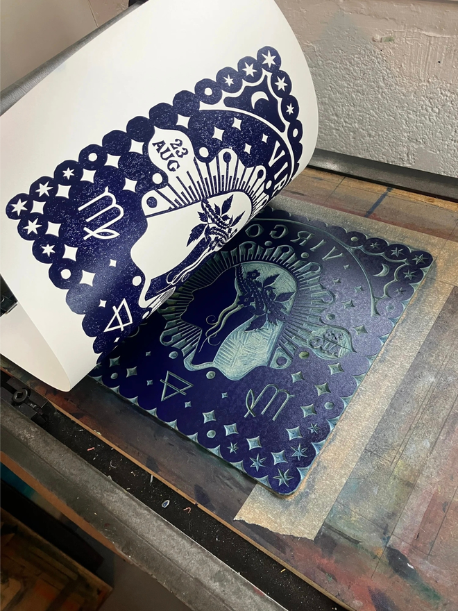 virgo zodiac linocut. a human side profile and zodiac symbols linocut on a blue background.