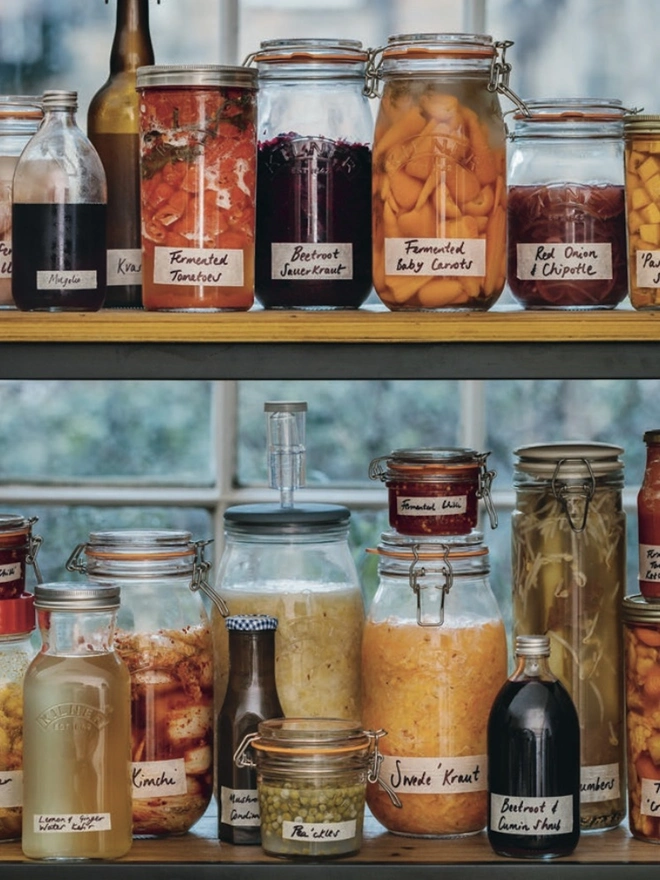 Jars containing colourful ferments on kitchen shelves