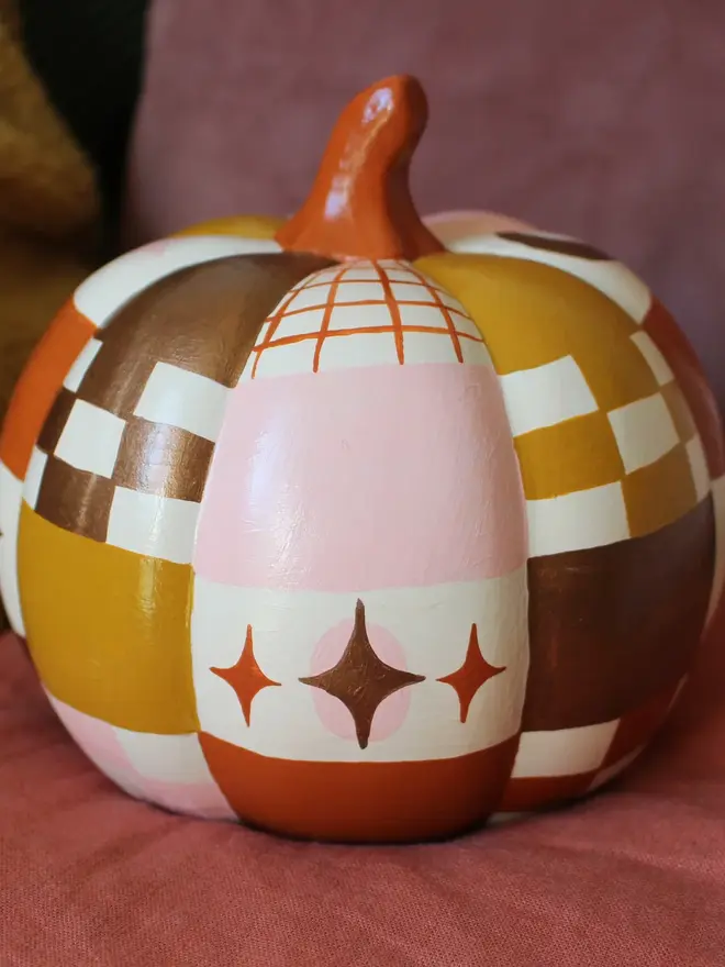 hand-painted celestial patchwork ceramic pumpkin. a ceramic pumpkin painted with patchwork colours of gold, pink, brown and stars and moons.