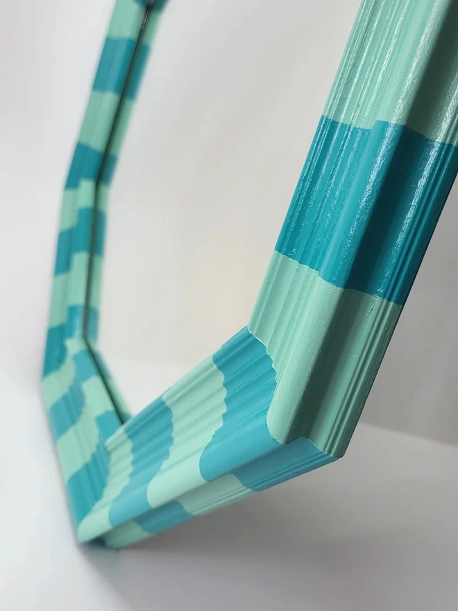 side close up view of hexagon shaped wooden mirror hand painted in mint green