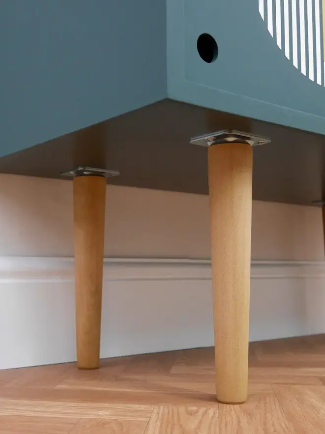 Teal mid-century record cupboard with sliding doors featuring bold geometric patterns in white and yellow.