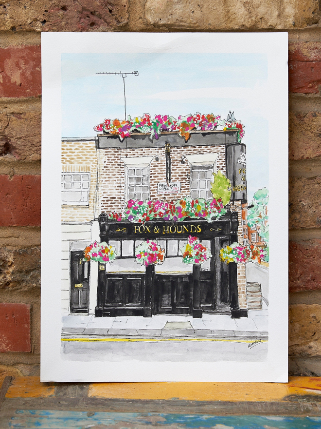 Watercolour painting portrait of a pub leaning against a brick wall
