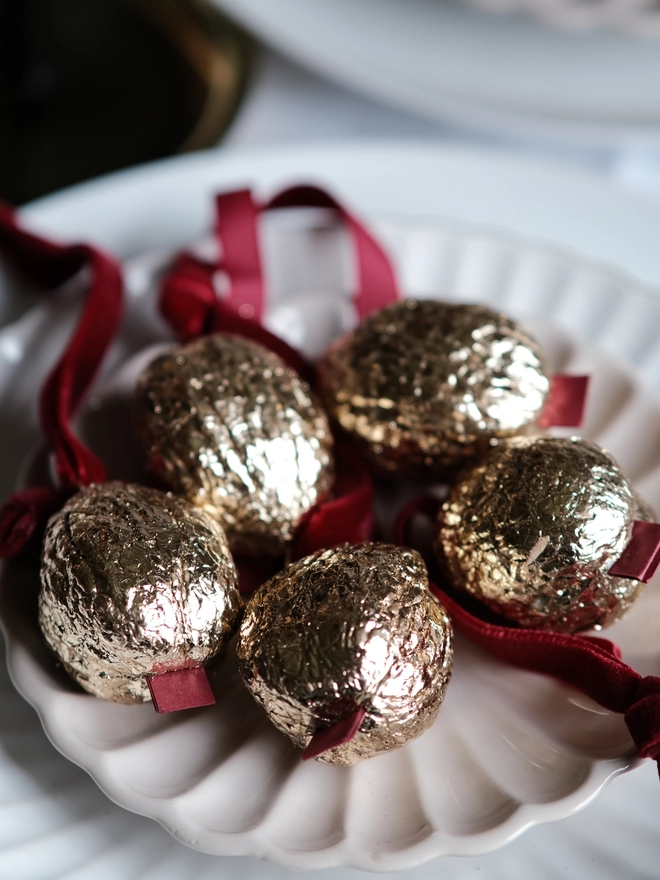 Handmade walnut Christmas ornament with delicate gold gilding, showing the natural shape and grain of the wood. A traditional, nostalgic Christmas tree decoration with timeless old-fashioned charm.