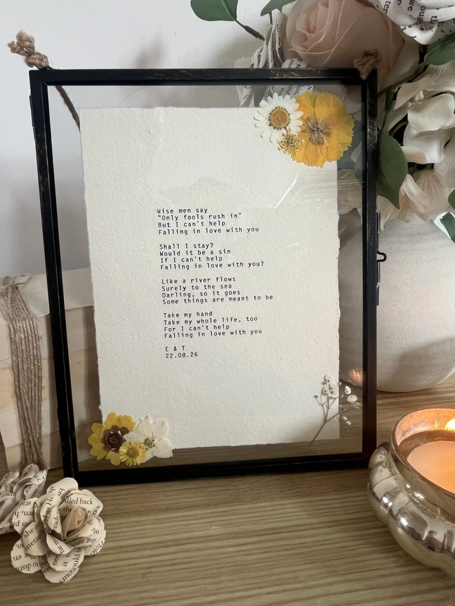 Framed typewriter print hand typed with an antique typewriter onto cotton rag handmade deckled paper. It is displayed in a black hanging rustic frame with gold brush detailing and decorated with real pressed dried flowers.