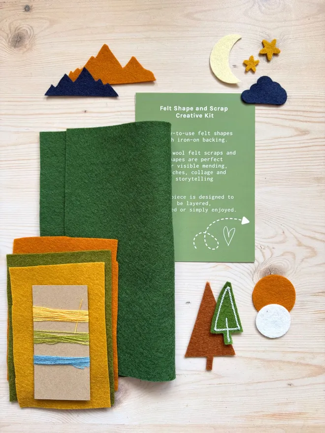 Felt shapes and scraps laid out with an instruction card on a wooden background