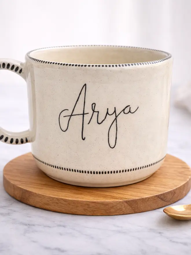 Ceramic mug with a child's writing saying 'Anya' on it 