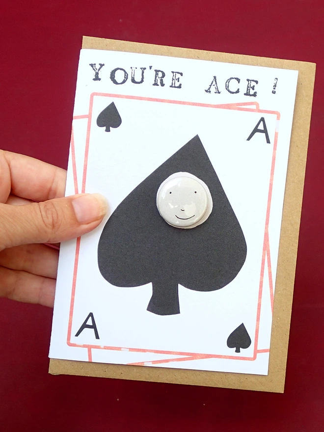 ace of spades greeting card with happy face pin badge